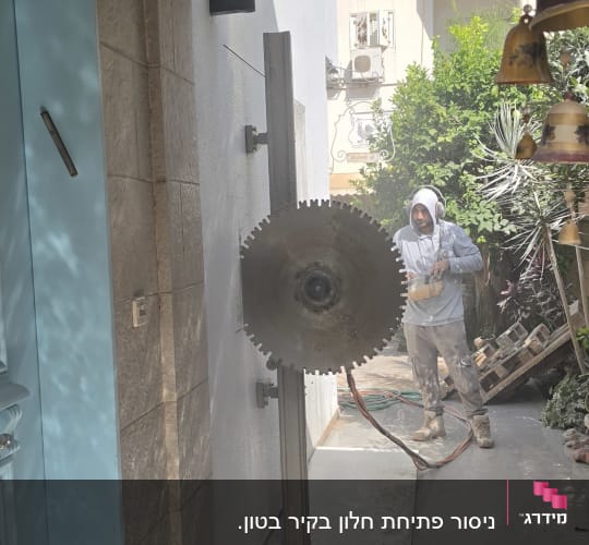 אדם עובד עם מסור גדול ליד קיר בטון